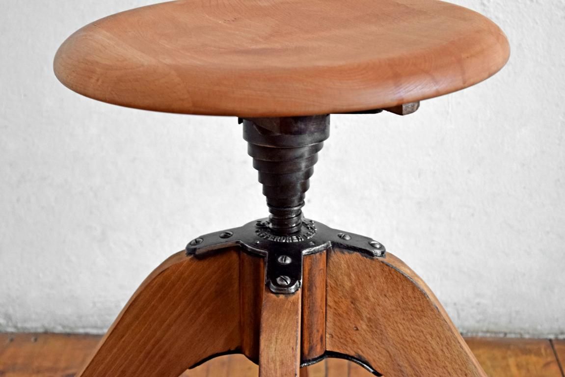 Detailansicht eines antiken Werkstatthockers mit gusseisernem Gewindekopf und massiven Holzbeinen, Illustration der materiellen Intelligenz und statischen Logik