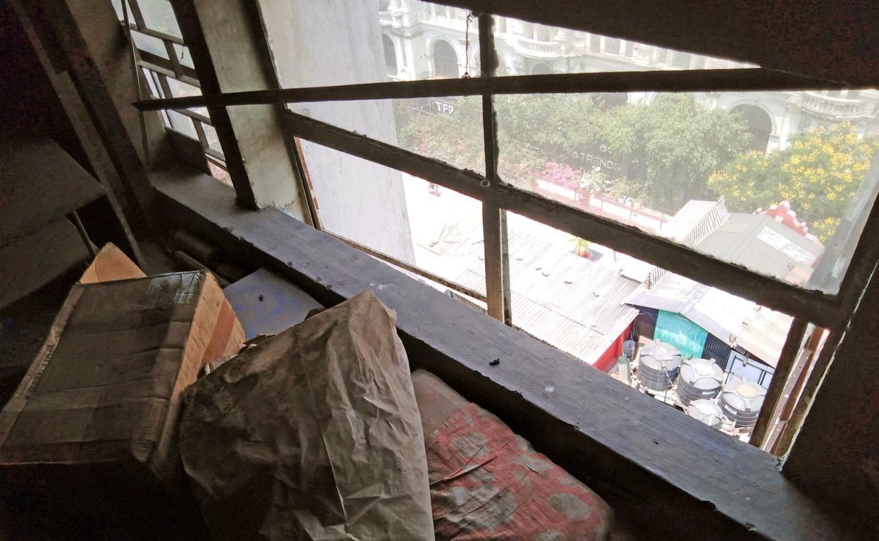 staubiges altes Fenster in einem leeren Bürohaus, im Vordergrund liegen alte Möbel und Gerümpel