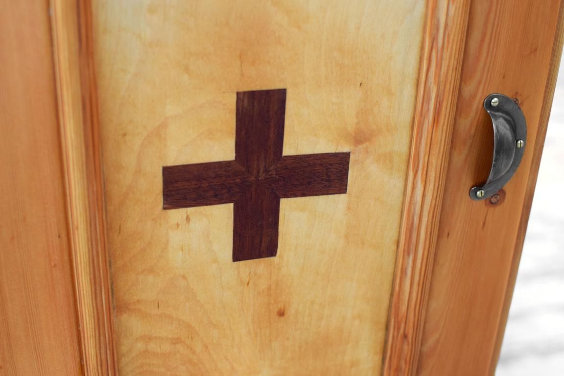 hölzerne Intarsie (rotes Kreuz) auf einem Medizinschrank