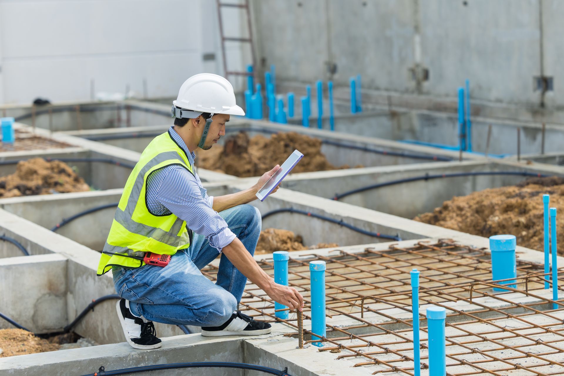 The inspector is checking rebar and layout during concrete foundation work.