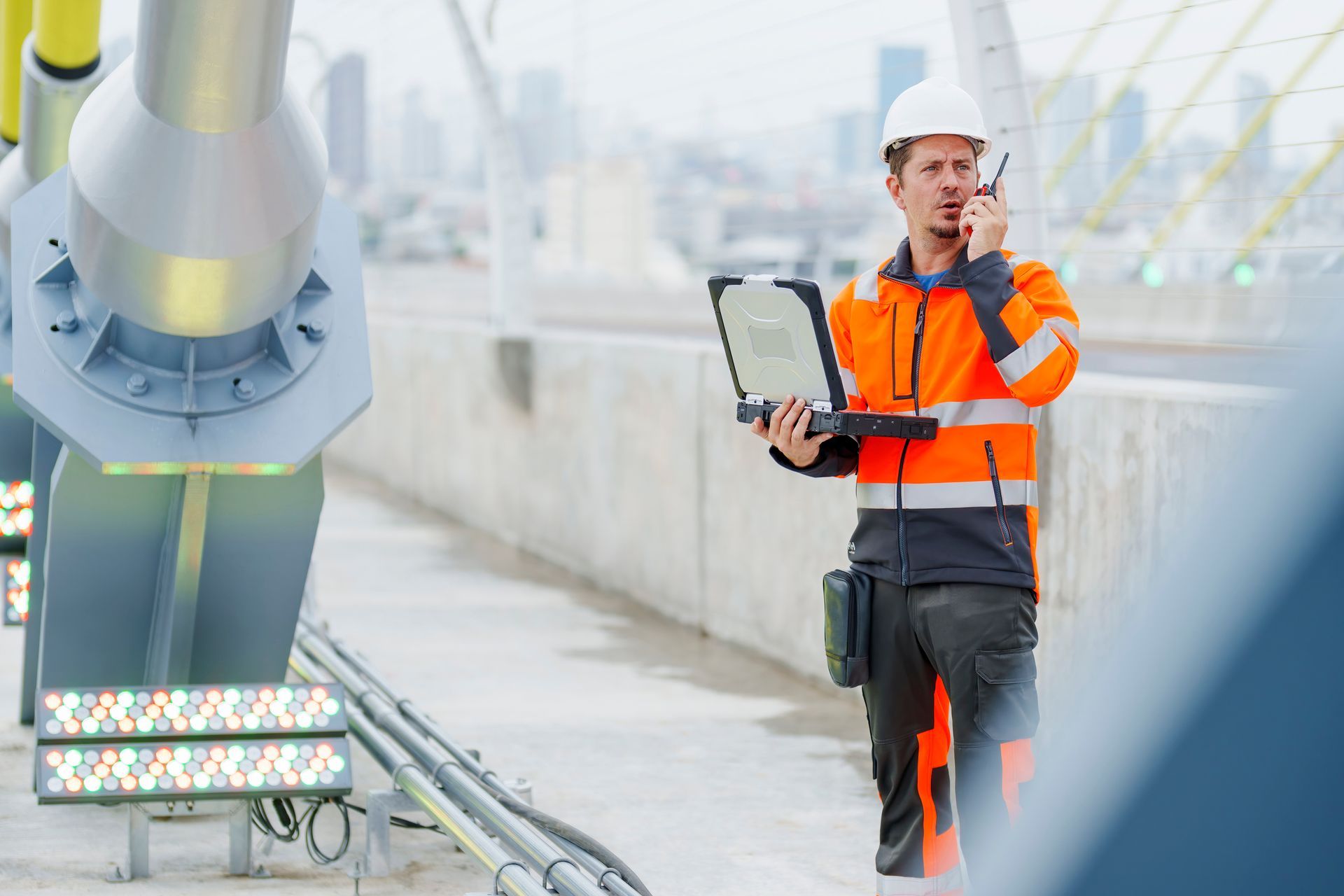 Residential structural engineer inspecting bridge supports with laptop and radio on construction site. Residential structural engineer inspecting bridge supports with laptop and radio on construction site.