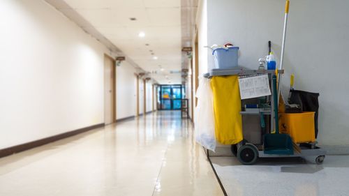 A cleaning cart with a mop and bucket in a hallway.