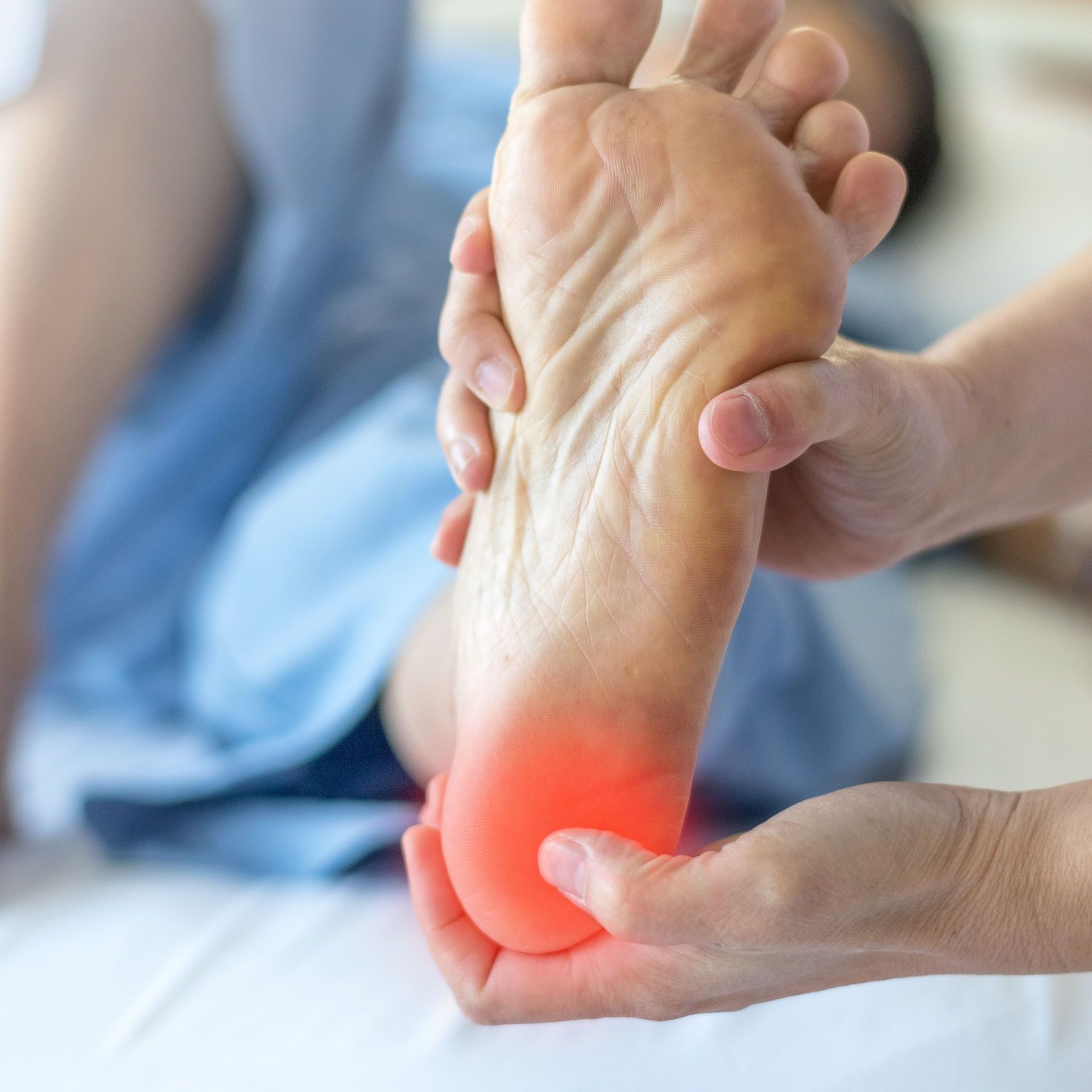 A doctor is holding a model of a foot in his hands.