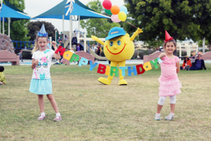 Two little girls holding a banner that says happy birthday