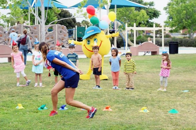 A group of children are playing with a mascot in a park.