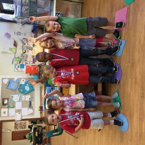 A group of children are posing for a picture in a classroom holding medals.