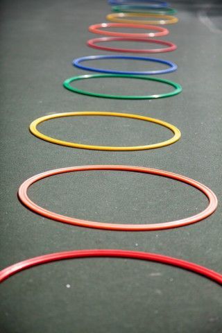A row of colorful hula hoops are lined up on the ground