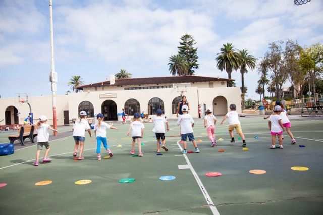 A group of children are playing on a court in front of a building.