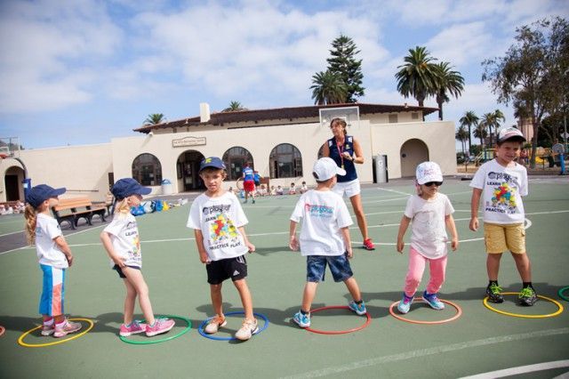 A group of children are playing with hula hoops on a court.