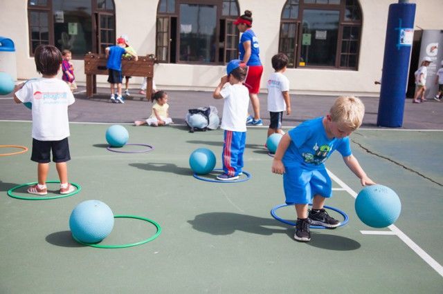 A group of children are playing with balls on a court