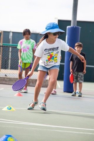 A young girl is holding a tennis racquet on a tennis court.