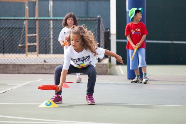 A group of children are playing frisbee on a tennis court