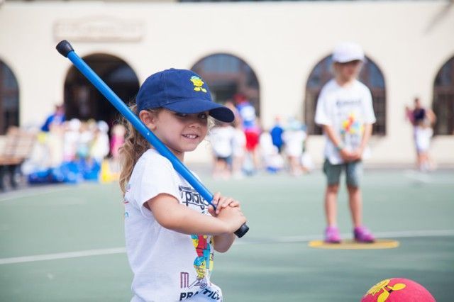 A little girl in a blue hat is holding a baseball bat