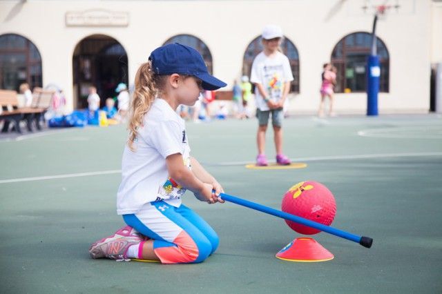 A little girl is playing with a ball on a court.