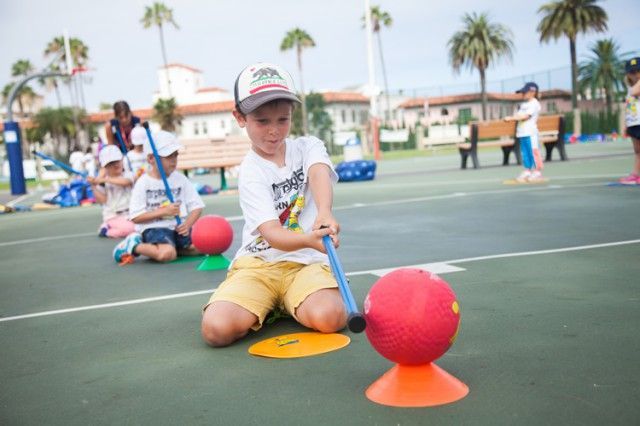 A young boy is playing with a ball on a court.