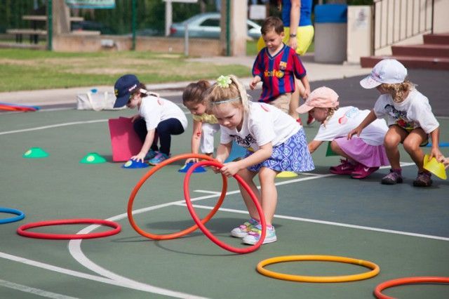 A group of children are playing with hula hoops on a court.