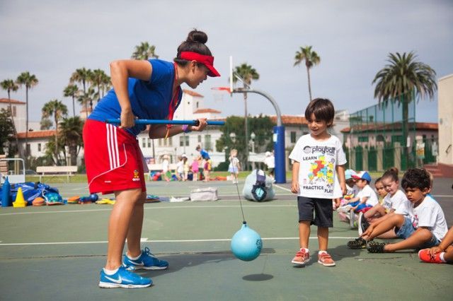 A woman is playing with a boy on a tennis court.