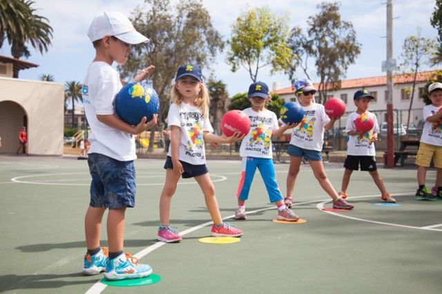 A group of children are playing with balls on a court.