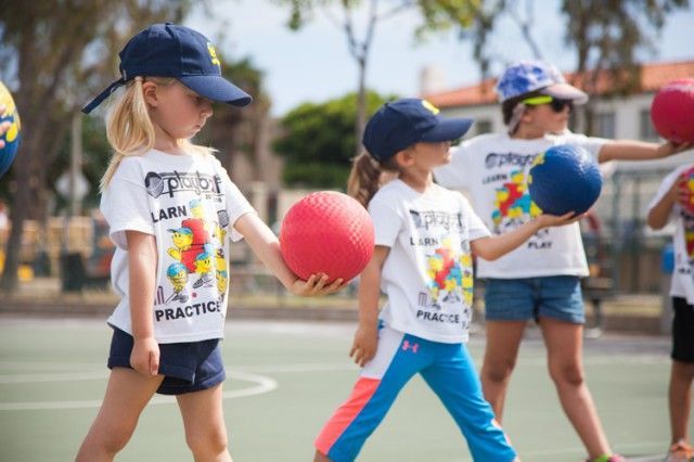 A group of children are playing with balls on a court.