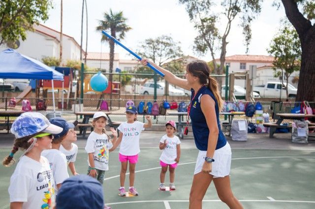 A woman is throwing a frisbee at a group of children