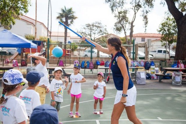 A woman is throwing a frisbee to a group of children on a court.