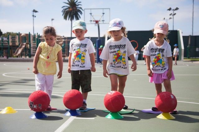 A group of children are playing with balls on a basketball court