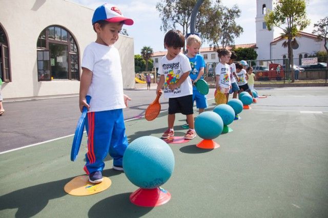 A group of children are playing with balls on a court