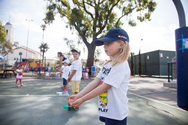 A little girl wearing a white shirt that says play on it