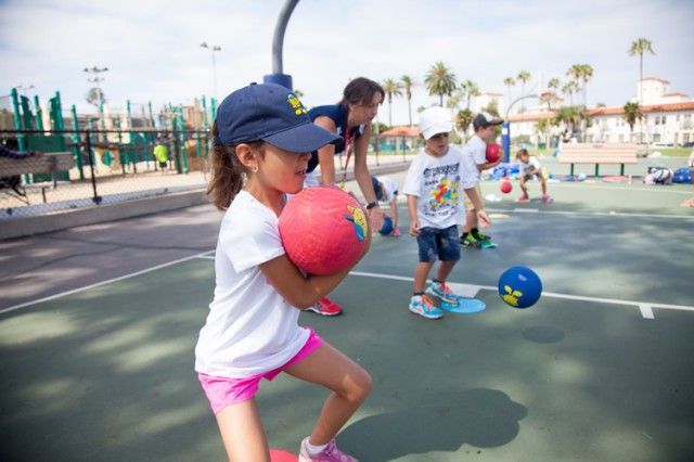 A group of children are playing with balls on a court.