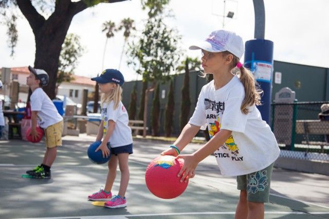 A group of children are playing with balls on a court.