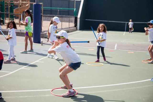 A group of young girls are playing tennis on a court.