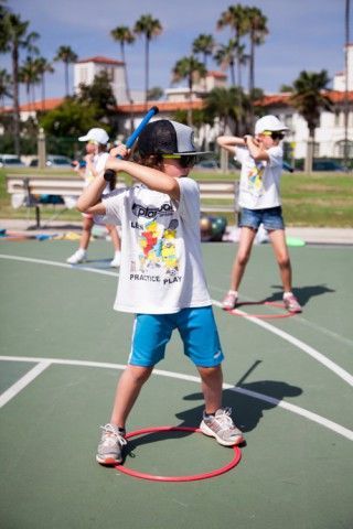 A young boy is swinging a baseball bat on a tennis court.
