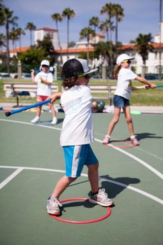 Two young girls are playing with hula hoops on a court.