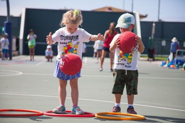 A boy and a girl are playing with balls on a court.
