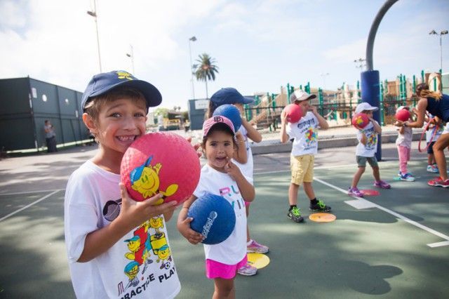 A group of children are holding balls on a basketball court.