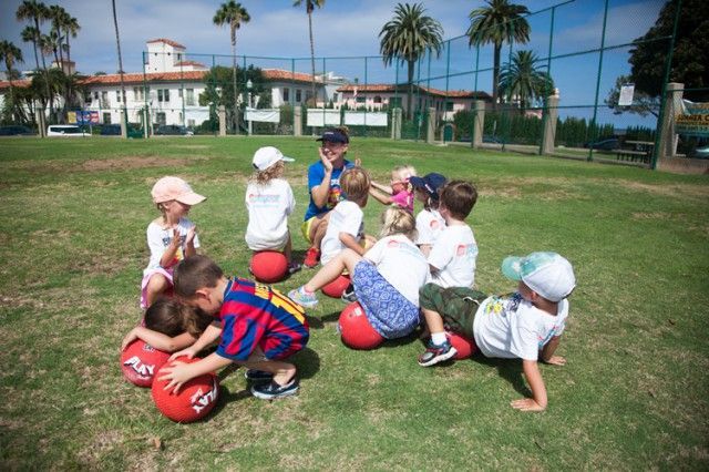A group of children are playing with balls in a field.