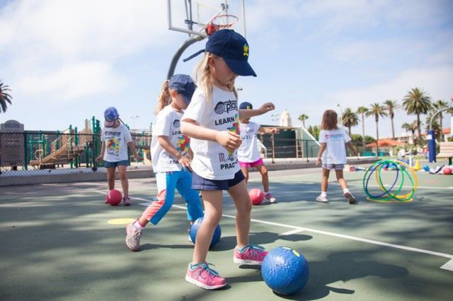 A group of young girls are playing soccer on a court.