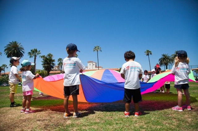 A group of children are playing with a colorful parachute in a park.