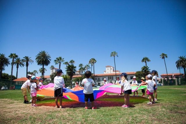 A group of children are playing with parachutes in a field.