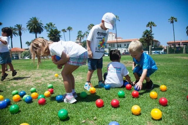A group of children are playing with colorful balls on the grass.