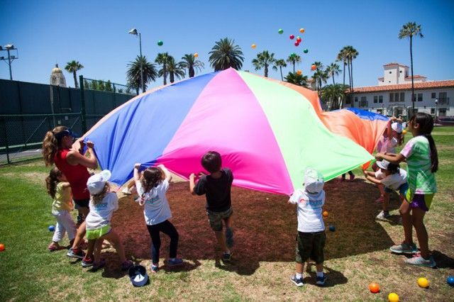 A group of children are playing with a colorful parachute.