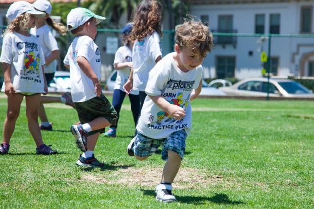 A group of children are running on a grassy field.