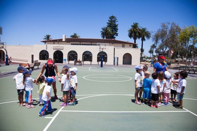 A group of children are standing in a circle on a basketball court.
