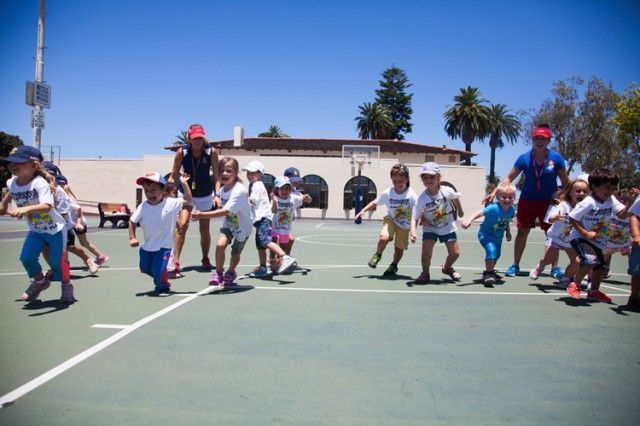 A group of children are running on a tennis court.