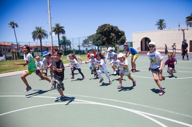 A group of children are running on a basketball court.