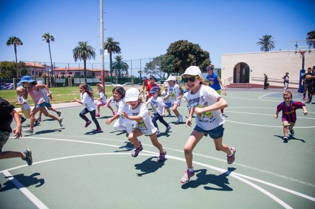 A group of children are running on a basketball court.