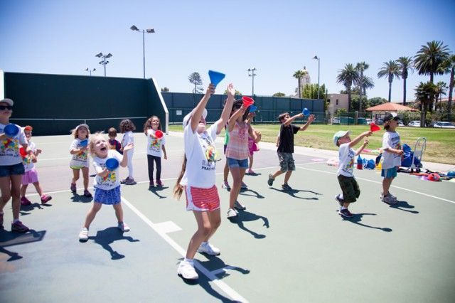 A group of children are playing on a tennis court