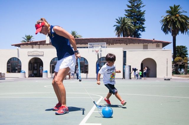 A woman and a child are playing soccer on a court.