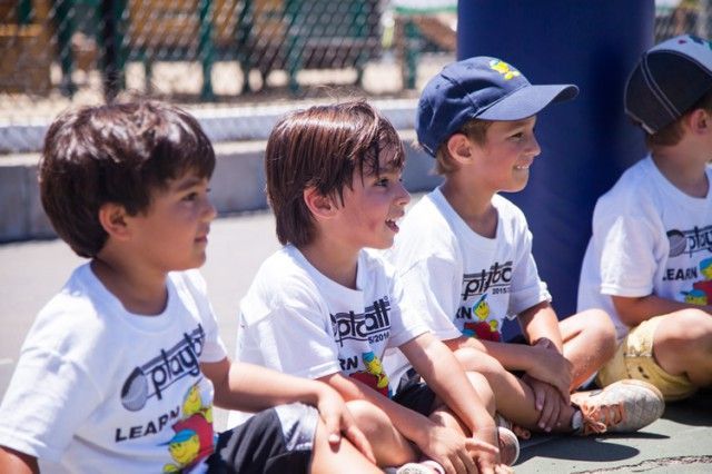 A group of young boys are sitting on the ground wearing shirts that say leap