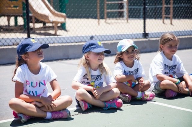 A group of young girls are sitting on a tennis court.